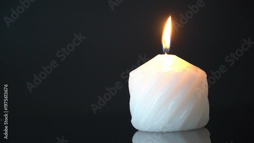 Candle burning softly. A white candle burns with a soft flame in the dark. High quality FullHD footage