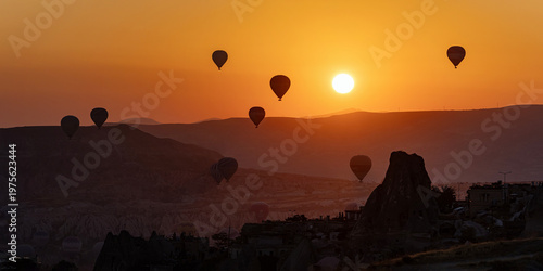 Hot air balloons float over the mountains of Cappadocia at sunrise.