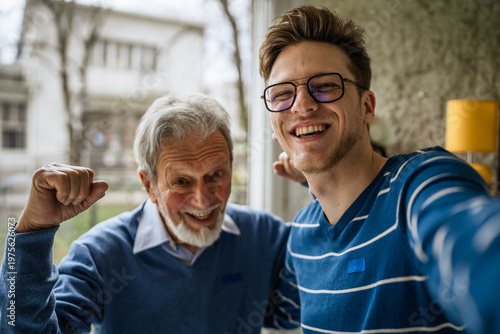 Fotografi Grandfather and grandson celebrating success together taking selfie