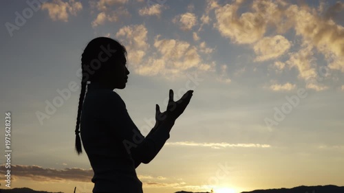  silhouette of a woman open palm prayer on mountain top.