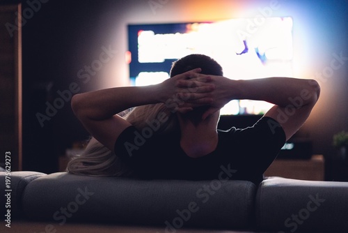 Couple relaxing together on couch watching TV in dimly lit room