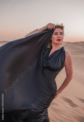 Close up portrait of elegant blond woman in black dress in desert, UAE. 