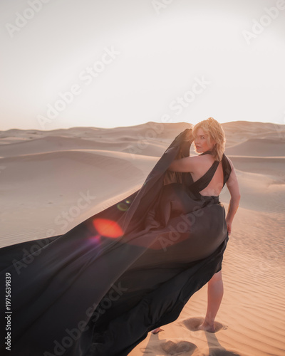 Close up portrait of elegant blond woman in black dress in desert, UAE. 