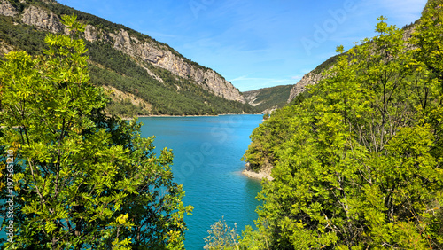 Foto Lake Castillon's turquoise water winding through mountains and lush green trees, Alpes-de-Haute-Provence, France, Europe