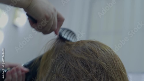 The master hairdresser does the hair styling with a hair dryer and comb