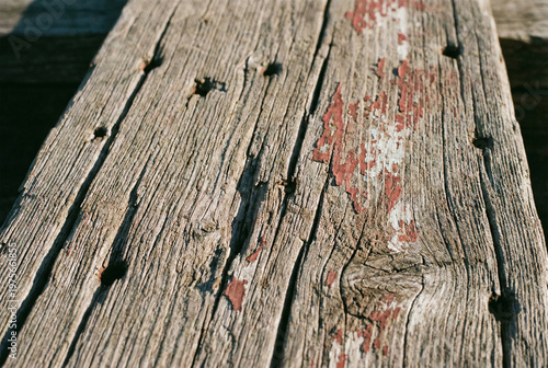 Close-up texture of old weathered wooden planks with rusty nails, cracked paint and natural grain pattern. Grunge rustic background surface.