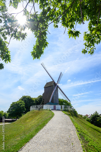 Wooden windmill on grassy hill under blue sky