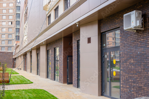 A row of modern building entrances with glass doors and air conditioning units on the exterior wall. commercial building, storefronts, urban architecture.