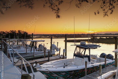 sunrise over the salt marsh of Murrells Inlet with boats and the waterfront boardwalk in the foreground