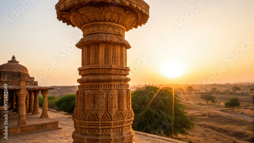 Ancient golden pillar in indian city of Jaisalmer glows warmly at sunset with desert landscape and historic architecture in background