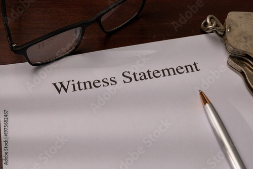 Close-up of a Witness Statement Document with Glasses, Pen, and Handcuffs on a Desk