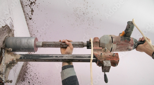Fotografie Caucasian worker using concrete core drilling machine.