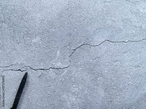Cracked concrete texture with pen creating minimal composition background representing problem, idea or concept space