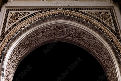 Richly carved stucco arch with floral and geometric motifs, doorway to a room in the gallery around the Small Riad-Bahia Palace. Marrakesh-Morocco-266