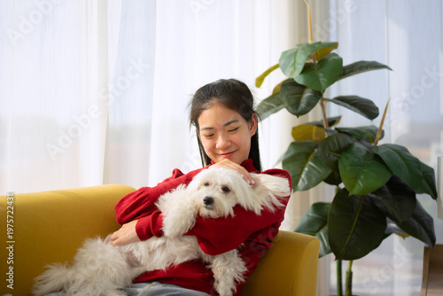 The Asian pretty woman is spending leisure time with her dog at the living room.