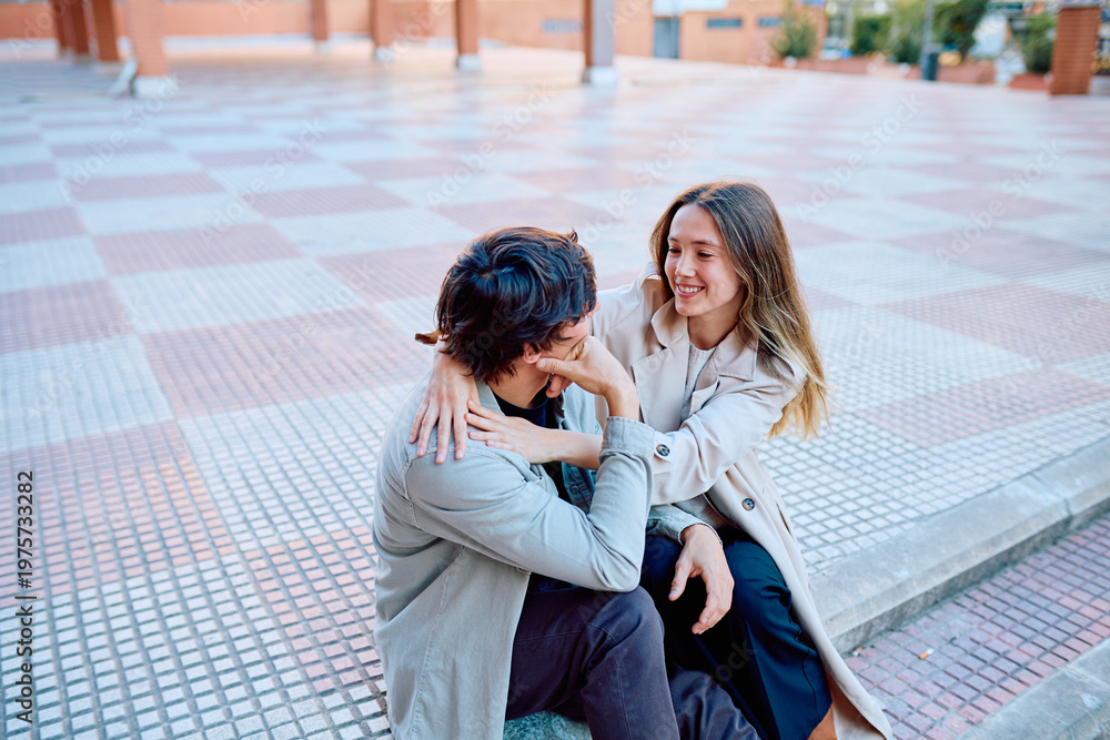 Fototapeta premium Happy young couple embracing and laughing in an urban setting, representing love, connection, and relationship goals