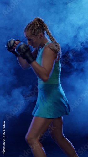 Vertical video, woman pro fighter beats a punching bag, hard training in the boxing gym, fighter trains his punches, strength fit body.