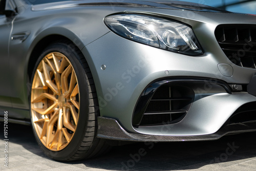 Close-up of matte grey luxury sport car with gold alloy wheels