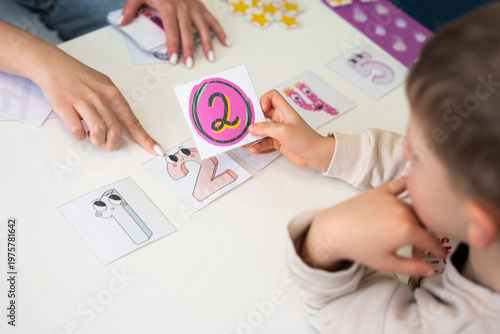 Close-up of a child and woman playing an educational number matching game