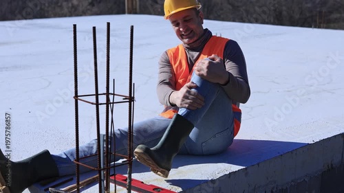 Construction worker having a accident and injured knee and leg on a construction site outdoors.