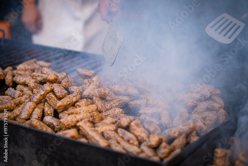 View of sizzling cevapi on a smoky grill, tender meat browning under a spatula's touch, a feast for the senses, fragrant steam rising, Pula, Istria County, Croatia.