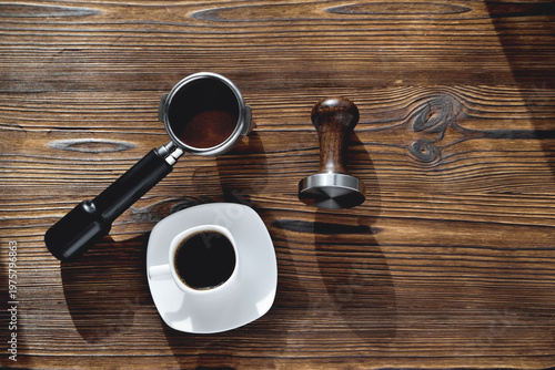 Photos a cup of coffee, a coffee horn and a tamper on a wooden background, selective fo