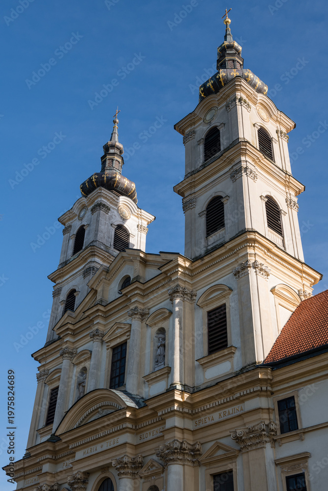 Fototapeta premium Low angle view of a baroque Basilica of the Seven Sorrows of the Blessed Virgin Mary with twin ornate towers and classic stone facade under a clear sky, Sastin-Straze, Slovakia