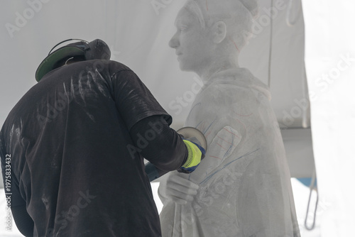 Sculptor refining statue with electric carving tool