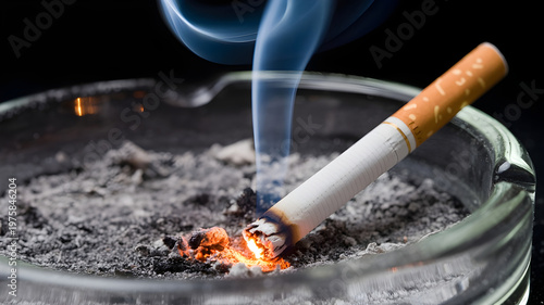 A lit cigarette resting in a glass ashtray with burning embers and smoke rising