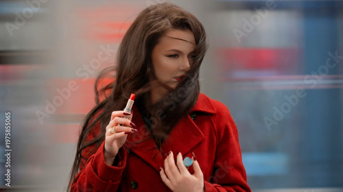 Elegant brunette with red lipstick trying to fix makeup as train wind ruins her hair