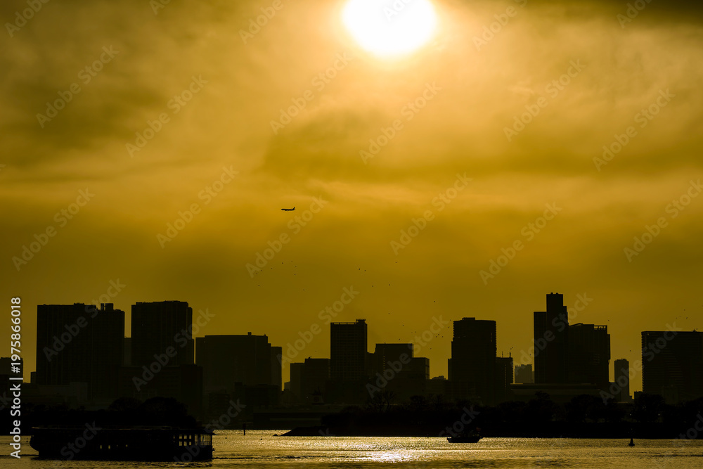 Obraz premium Silhouetted Tokyo skyline under a dramatic golden sunset in Odaiba, Japan