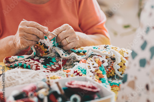Canvas Print Elderly woman crocheting a colorful handmade blanket with careful hands at a coz