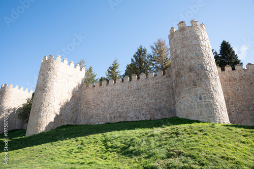 Historic stone walls with towers and greenery.. Walls of Ávila in Spain