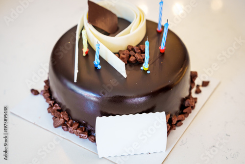 . Delicious dark chocolate birthday cake with candles and white chocolate decor.