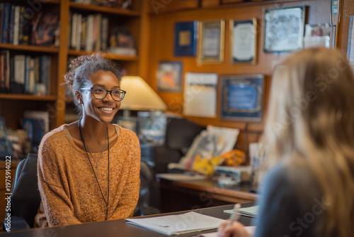 Professor meeting student during office hours in cozy setting.