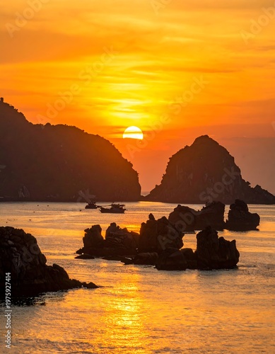 Golden sunset over ocean, rocky formations, and silhouette hills