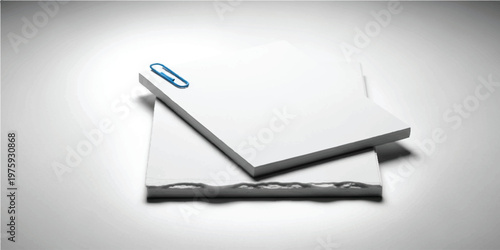 Two stacked white rectangular paper pads with a single blue metal paperclip attached to the corner on a plain light gray background