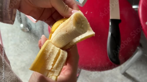 Hands, diet and a person peeling a banana in studio on a gray background closeup for health or nutrition. Fruit, food or healthy eating and a vegan adult with fresh produce for hunger.