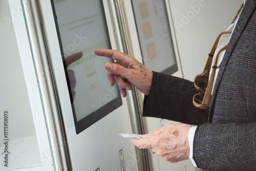 Elderly person interacts with touchscreen to request medical service at Health center.
