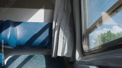 Empty seats in a sleeper train compartment moving past a sunny landscape. Sunlight creates moving shadows inside the nostalgic cabin