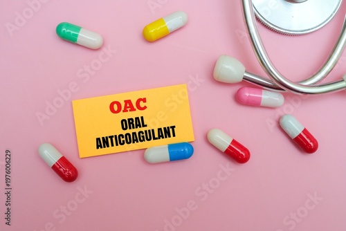 Obraz na płótnie A yellow note with the text OAC - ORAL ANTICOAGULANT surrounded by various multi colored medicinal capsules and a stethoscope