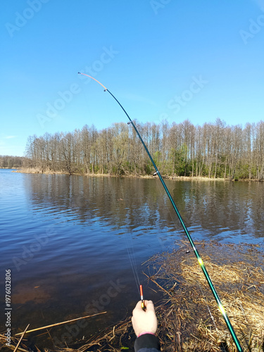 Getting ready to cast the fishing rod into the water. A float in one hand, a fishing rod in the other.