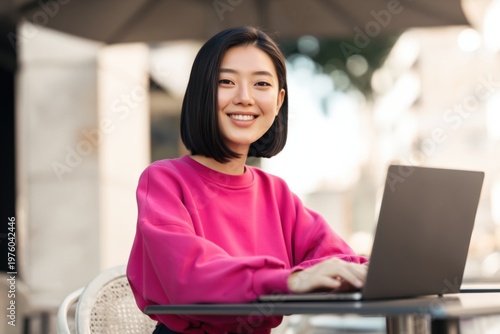 Young woman smiling while using laptop at outdoor cafe Free Download Young woman smiling while using laptop at outdoor cafe - GFXLoad