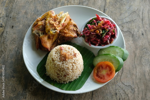 ayam geprek sambal kecombrang, kampong fried chicken with torch ginger chili sauce and sliced tomato and cucumber. Indonesian food.
