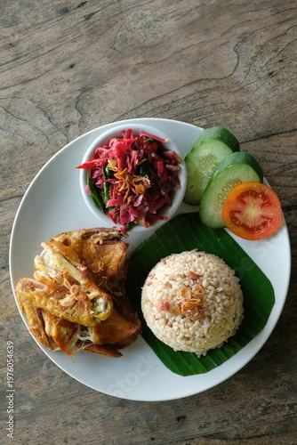 ayam geprek sambal kecombrang, kampong fried chicken with torch ginger chili sauce and sliced tomato and cucumber. Indonesian food.
