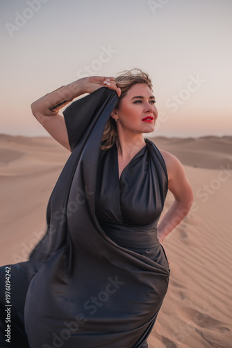 Close up portrait of elegant blond woman in black dress in desert, UAE. 