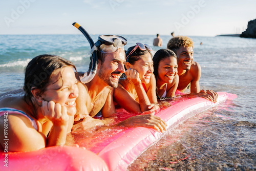 Foto Diverse young friends are joyfully laughing and relaxing on a pink inflatable ra
