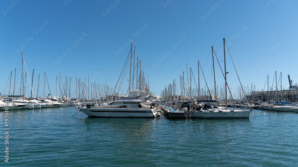 Fototapeta premium Luxury yachts and sailboats moored in marina under clear blue sky