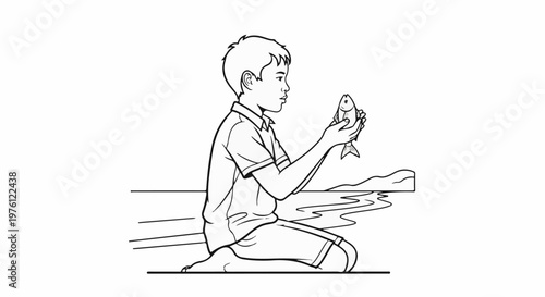 A young boy kneels by the water holding a small fish in his hands