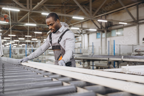Factory worker handling PVC window profile on production line